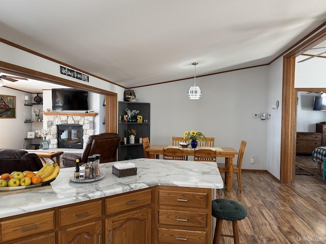 93 E Johnson Lake Rd, Gwinn, MI 49841 - kitchen featuring crown molding, dark wood-style floors, light countertops, a stone fireplace, and brown cabinetry