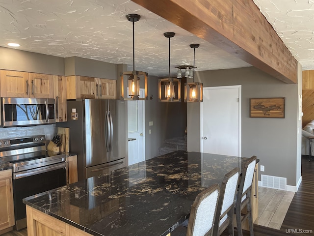 52170 Canal Rd, Houghton, MI 49931 - kitchen featuring stainless steel appliances, dark stone counters, wood finished floors, and pendant lighting