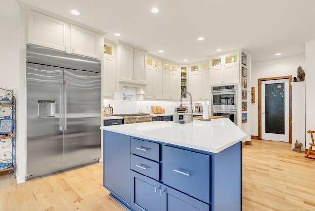 3905 Lakeshore Rd, Lexington, MI 48450 - kitchen with appliances with stainless steel finishes, blue cabinets, light wood-style flooring, white cabinets, and recessed lighting