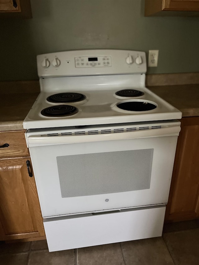 1106 Marsac St, Bay City, MI 48708 - kitchen with electric range, brown cabinets, and dark tile patterned floors