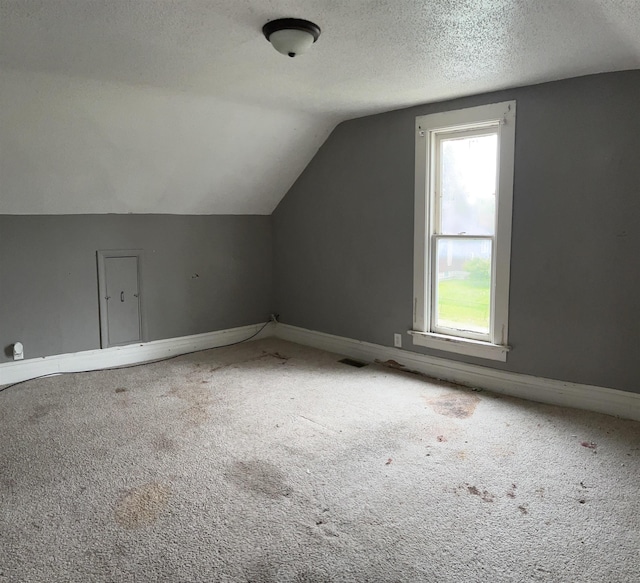 1106 Marsac St, Bay City, MI 48708 - bonus room featuring carpet flooring, vaulted ceiling, a textured ceiling, and baseboards