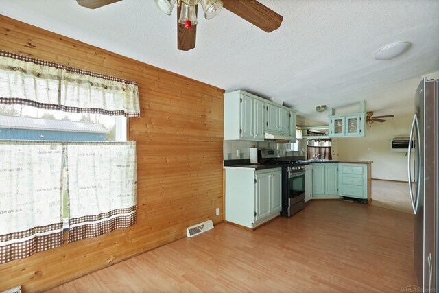 3909 Higgins Rd, Vassar, MI 48768 - kitchen featuring appliances with stainless steel finishes, ceiling fan, green cabinetry, dark countertops, and wooden walls