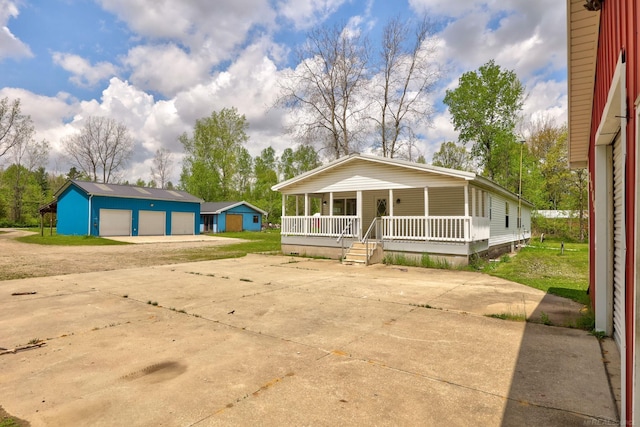 3909 Higgins Rd, Vassar, MI 48768 - view of front of home with a porch, driveway, a detached garage, and an outbuilding