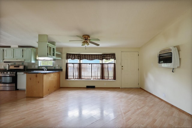 3909 Higgins Rd, Vassar, MI 48768 - kitchen featuring green cabinets, heating unit, stainless steel range with gas stovetop, under cabinet range hood, and light wood-type flooring