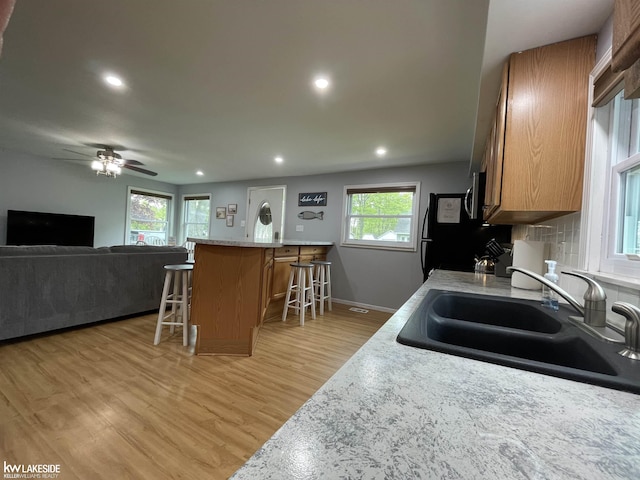 7314 Aspen Rd, Lexington, MI 48450 - kitchen featuring a sink, a breakfast bar area, stainless steel microwave, light wood-style floors, and recessed lighting