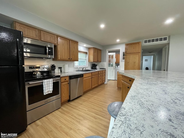 7314 Aspen Rd, Lexington, MI 48450 - kitchen featuring stainless steel appliances, light wood-style flooring, light countertops, a sink, and brown cabinets