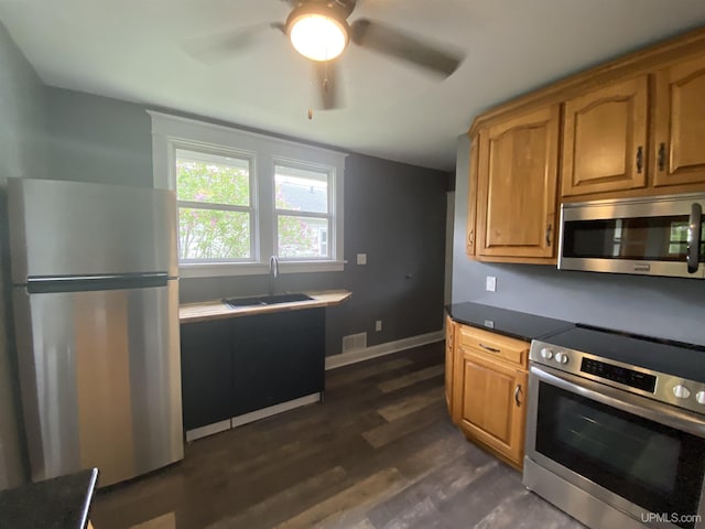 317 Lane Ave, Iron Mountain, MI 49802 - kitchen featuring stainless steel appliances, a sink, dark wood finished floors, a ceiling fan, and dark countertops