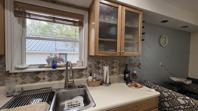 7741 White Birch St, Farwell, MI 48622 - kitchen featuring tasteful backsplash, glass insert cabinets, a sink, light countertops, and brown cabinetry