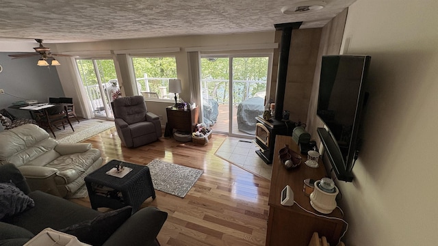 7741 White Birch St, Farwell, MI 48622 - living room featuring a wood stove, light wood-type flooring, ceiling fan, and a textured ceiling