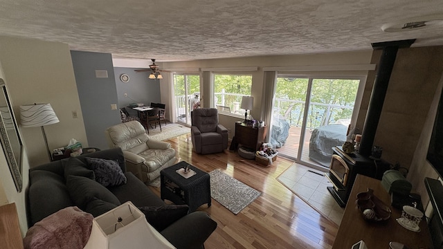 7741 White Birch St, Farwell, MI 48622 - living area with a wood stove, a textured ceiling, light wood-style flooring, and ceiling fan