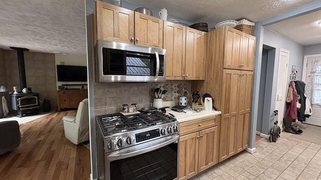 7741 White Birch St, Farwell, MI 48622 - kitchen with stainless steel appliances, a textured ceiling, a wood stove, light countertops, and open floor plan