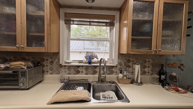 7741 White Birch St, Farwell, MI 48622 - kitchen featuring light countertops, decorative backsplash, glass insert cabinets, and brown cabinets