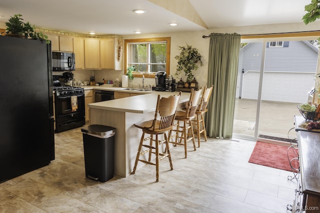 120 E Prospect St, Marquette, MI 49855 - kitchen with black appliances, light brown cabinetry, a peninsula, a sink, and light countertops