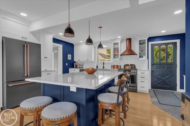 28800 Old N River Rd, Harrison Twp, MI 48045 - kitchen featuring stainless steel appliances, wall chimney range hood, a sink, white cabinets, and a kitchen breakfast bar