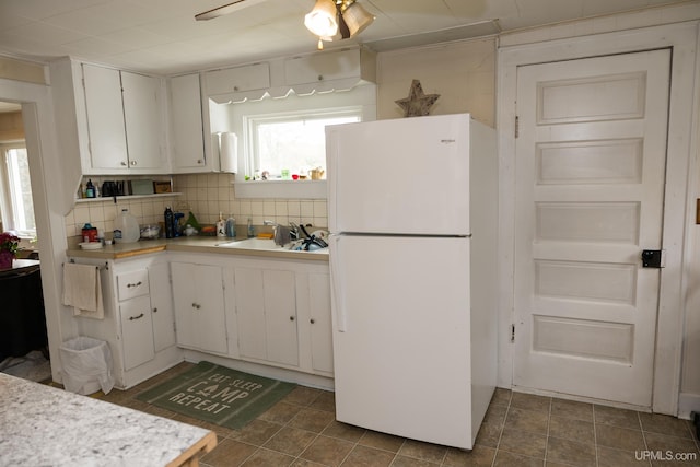 3110 County Road Fd Rd, Champion, MI 49814 - kitchen with freestanding refrigerator, a sink, light countertops, white cabinets, and decorative backsplash