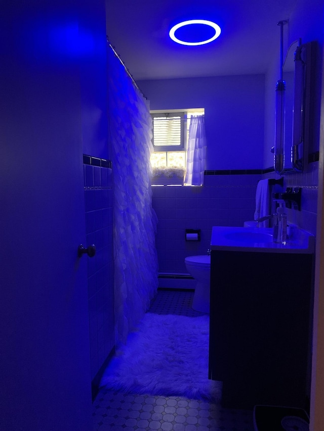 103 E Washington St, Coleman, MI 48618 - bathroom with toilet, vanity, baseboard heating, tile patterned flooring, and tile walls