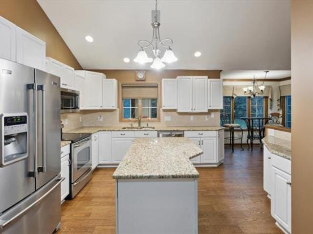 5631 W Spring Knoll Dr, Bay City, MI 48706 - kitchen featuring stainless steel appliances, a chandelier, a kitchen island, a sink, and white cabinetry