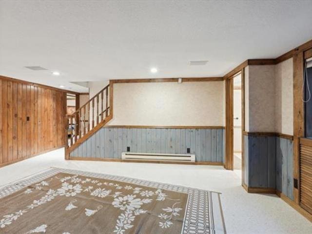 5631 W Spring Knoll Dr, Bay City, MI 48706 - finished below grade area featuring a baseboard heating unit, stairway, a wainscoted wall, wooden walls, and recessed lighting