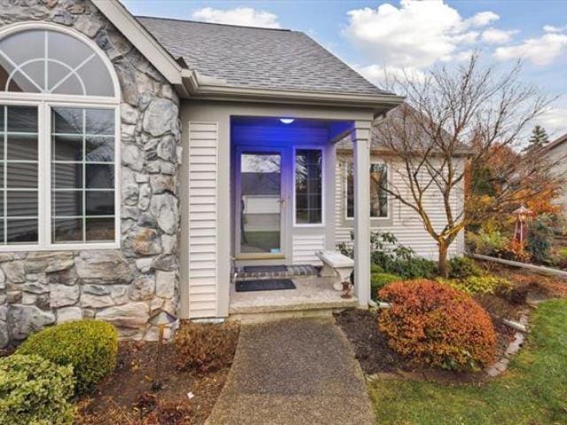 5631 W Spring Knoll Dr, Bay City, MI 48706 - view of exterior entry with stone siding and a shingled roof