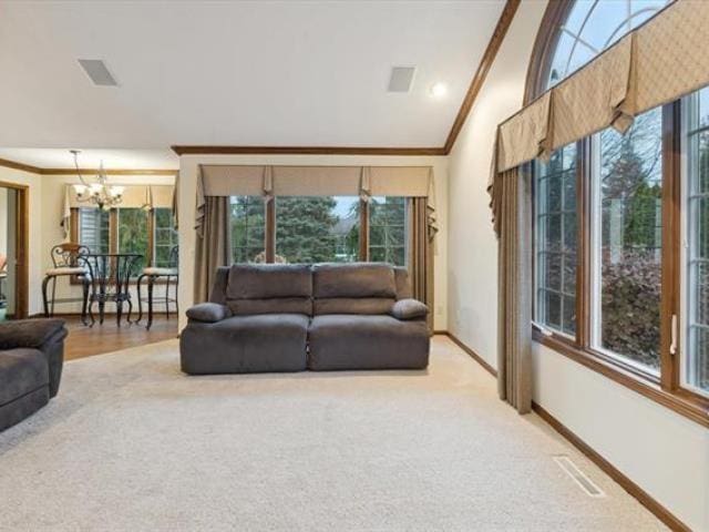 5631 W Spring Knoll Dr, Bay City, MI 48706 - carpeted living area featuring a chandelier, ornamental molding, baseboards, and lofted ceiling