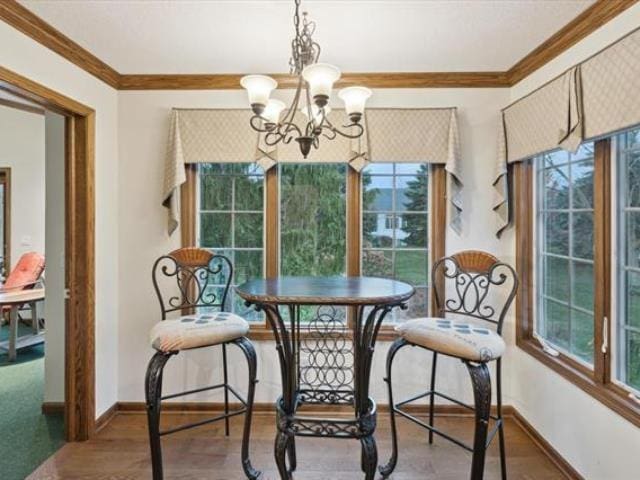 5631 W Spring Knoll Dr, Bay City, MI 48706 - dining area with a chandelier, crown molding, healthy amount of natural light, and baseboards