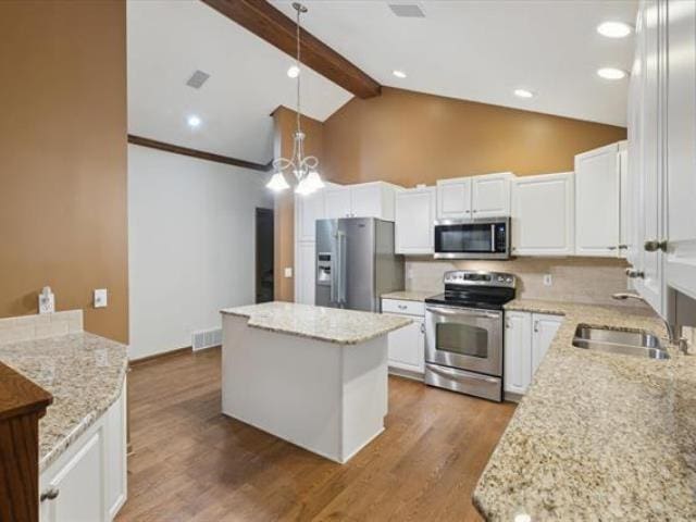 5631 W Spring Knoll Dr, Bay City, MI 48706 - kitchen with appliances with stainless steel finishes, a sink, a kitchen island, beam ceiling, and white cabinetry