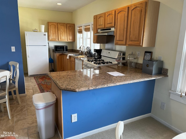2740 River Rd, Marysville, MI 48040 - kitchen with white appliances, under cabinet range hood, a peninsula, stone countertops, and brown cabinetry