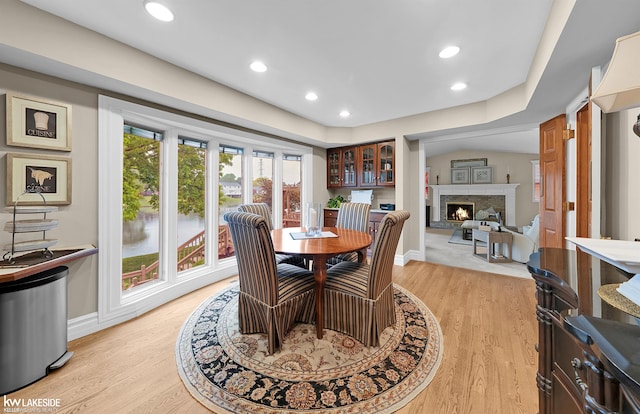 46713 Houghton Dr, Shelby Twp, MI 48315 - dining area with a lit fireplace, baseboards, light wood-style floors, and recessed lighting