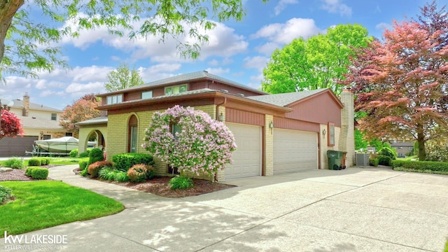 46713 Houghton Dr, Shelby Twp, MI 48315 - view of front of home with a garage, concrete driveway, a chimney, and brick siding