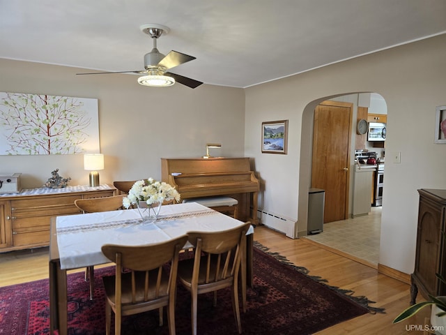 817 W Water St, Hancock, MI 49930 - dining area featuring arched walkways, a ceiling fan, baseboard heating, and light wood-style floors