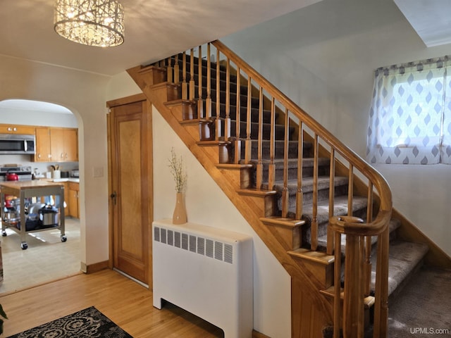 817 W Water St, Hancock, MI 49930 - stairway featuring radiator heating unit, wood finished floors, arched walkways, baseboards, and a chandelier