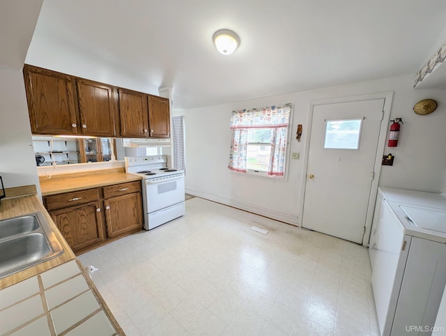 116 Caribou St, Gwinn, MI 49841 - kitchen with white range with electric stovetop, independent washer and dryer, light countertops, and brown cabinets