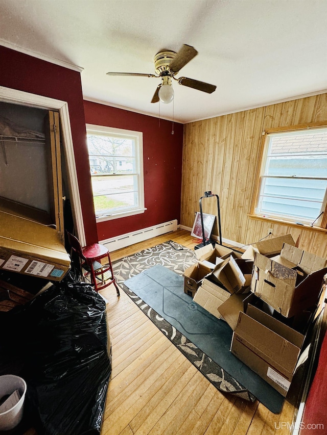 584 Elliott Ave, Ishpeming, MI 49849 - bedroom featuring wood finished floors, baseboard heating, wooden walls, baseboards, and a ceiling fan