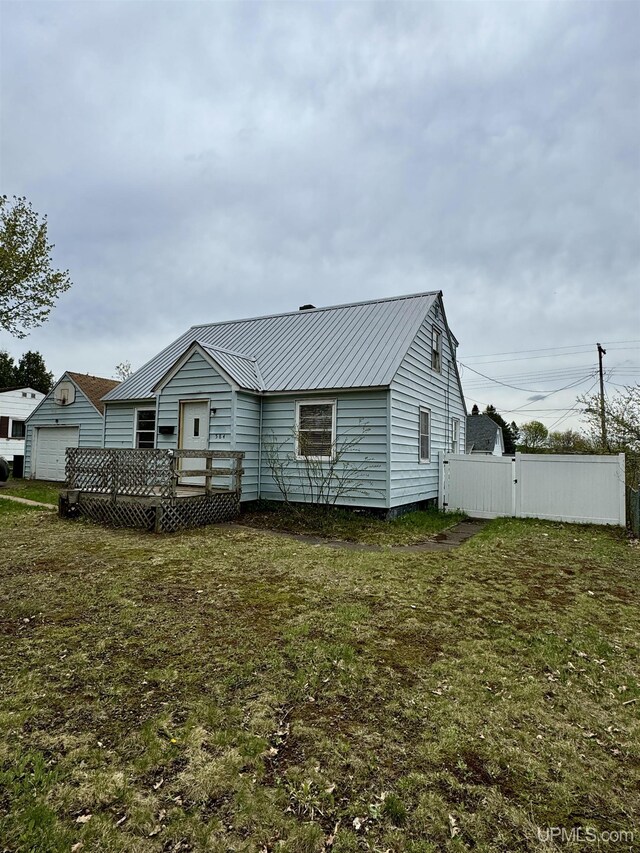 584 Elliott Ave, Ishpeming, MI 49849 - rear view of property featuring metal roof, a deck, and a detached garage