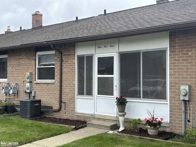 8401 18 Mile Rd Unit 154, Sterling Heights, MI 48313 - view of home's exterior featuring roof with shingles, brick siding, a chimney, and cooling unit