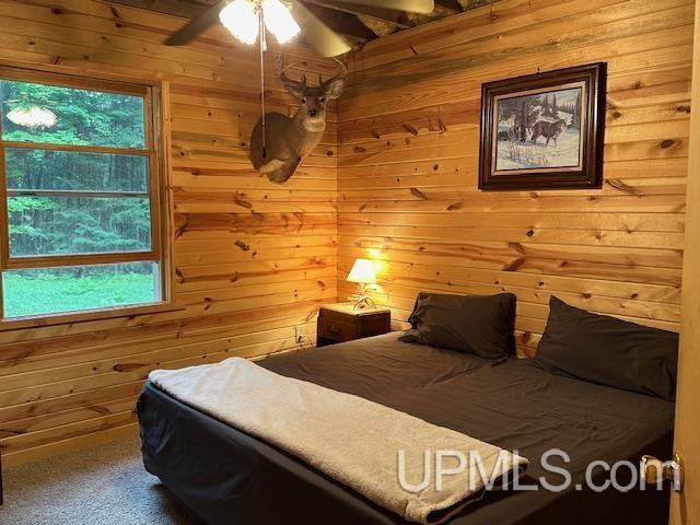 325 Mastodon Rd, Crystal Falls, MI 49920 - bedroom with wooden walls, carpet floors, and ceiling fan