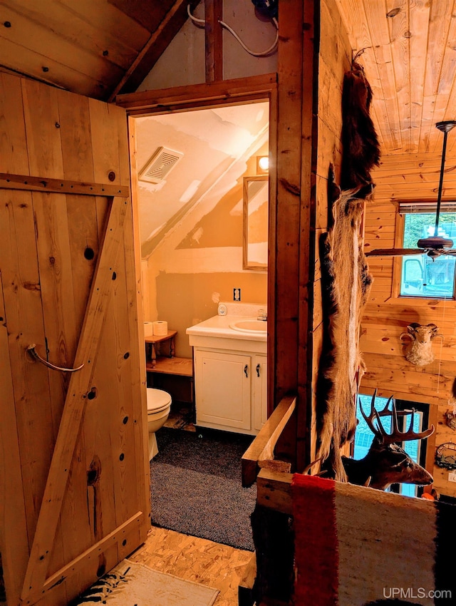 325 Mastodon Rd, Crystal Falls, MI 49920 - bathroom with wood ceiling, toilet, vanity, lofted ceiling, and wood walls