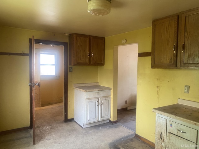 210 Birch St, Hancock, MI 49930 - kitchen with baseboards, unfinished concrete flooring, light countertops, and brown cabinets