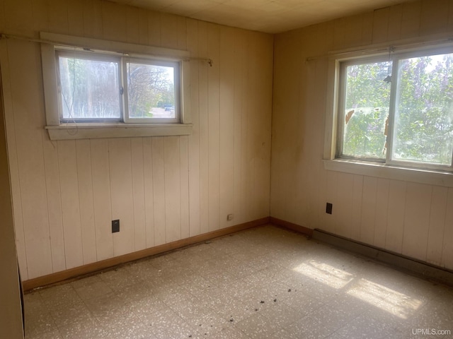 210 Birch St, Hancock, MI 49930 - spare room with tile patterned floors, wooden walls, and a baseboard heating unit