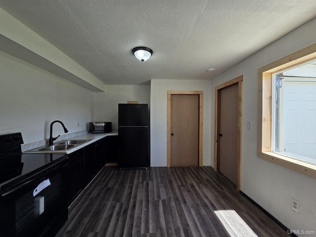 601 Range St, Manistique, MI 49854 - kitchen featuring black appliances, a sink, dark wood-style floors, a textured ceiling, and light countertops