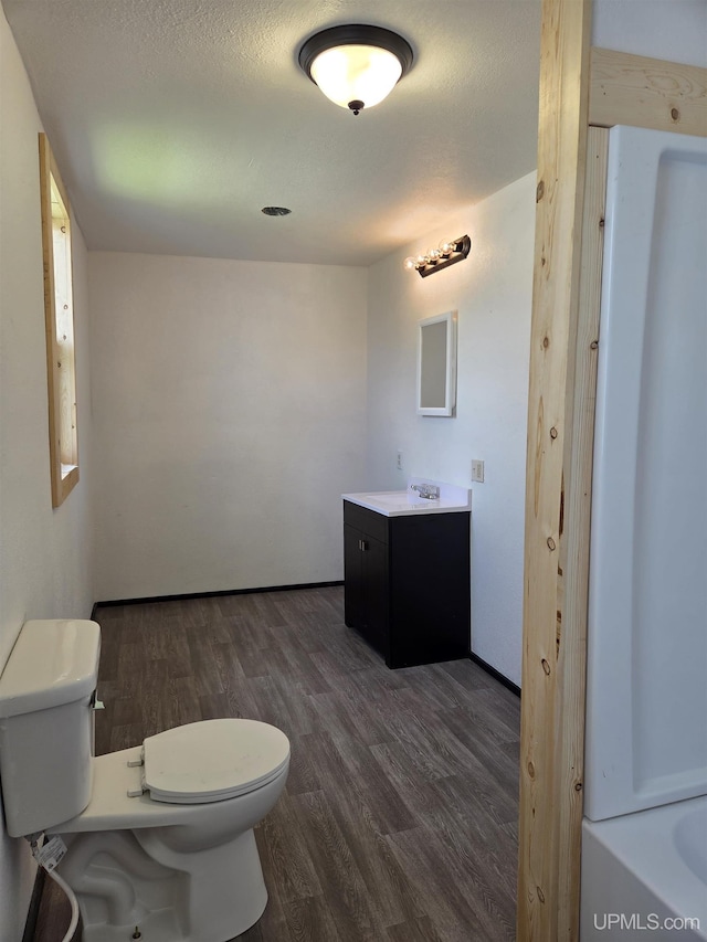601 Range St, Manistique, MI 49854 - bathroom with toilet, vanity, wood finished floors, and a bathtub