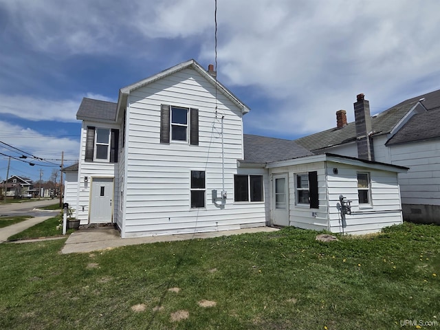 601 Range St, Manistique, MI 49854 - rear view of property with a shingled roof and a lawn