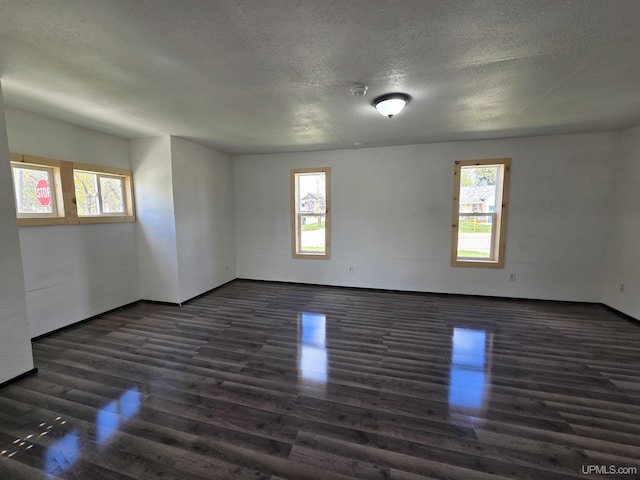 601 Range St, Manistique, MI 49854 - spare room with dark wood finished floors, healthy amount of natural light, a textured ceiling, and baseboards