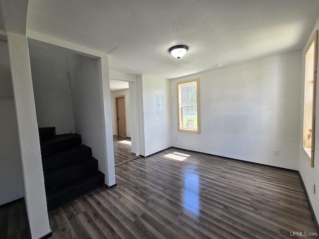 601 Range St, Manistique, MI 49854 - empty room with dark wood-type flooring, stairs, a textured ceiling, and electric panel