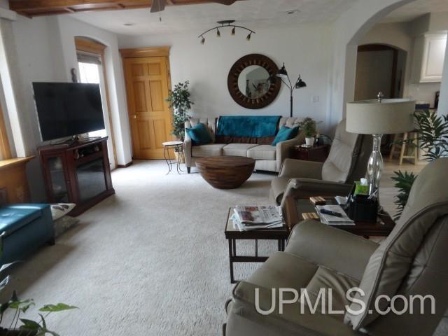 201 E Jewell St, Munising, MI 49862 - living area featuring arched walkways, light carpet, and a ceiling fan