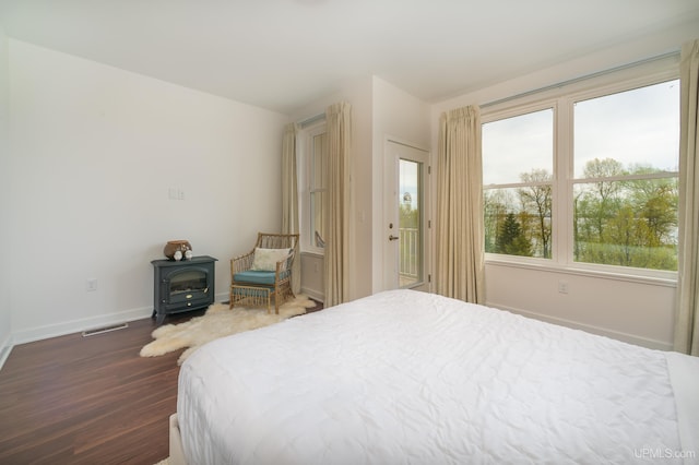 776 S Lakeshore Blvd, Marquette, MI 49855 - bedroom with a wood stove, dark wood-type flooring, baseboards, and access to exterior