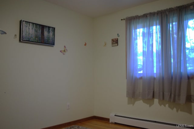 1001 Spruce St, Houghton, MI 49931 - empty room featuring a baseboard radiator, wood finished floors, and baseboards