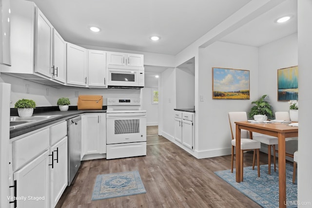 49058 Douglas St, Hancock, MI 49930 - kitchen featuring white appliances, dark countertops, dark wood finished floors, white cabinets, and recessed lighting