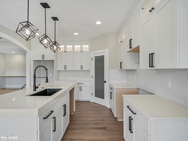 55127 Saint Paul Dr, Macomb Twp, MI 48042 - kitchen featuring a sink, wood finished floors, glass insert cabinets, recessed lighting, and a kitchen island with sink