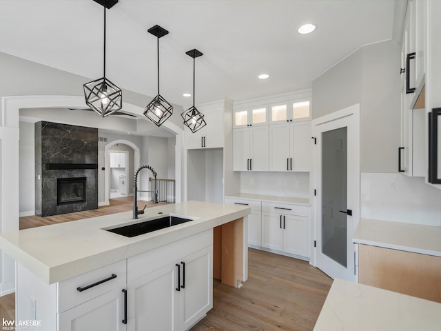 55127 Saint Paul Dr, Macomb Twp, MI 48042 - kitchen with a sink, light wood-style flooring, glass insert cabinets, pendant lighting, and white cabinetry